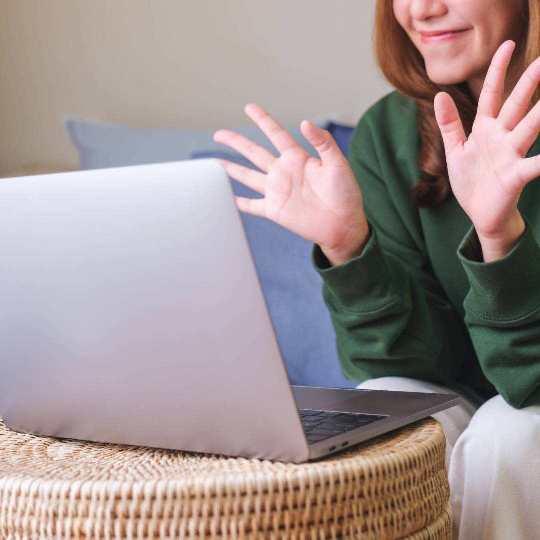 Closeup of a young woman using laptop computer for video call and working or studying online at home